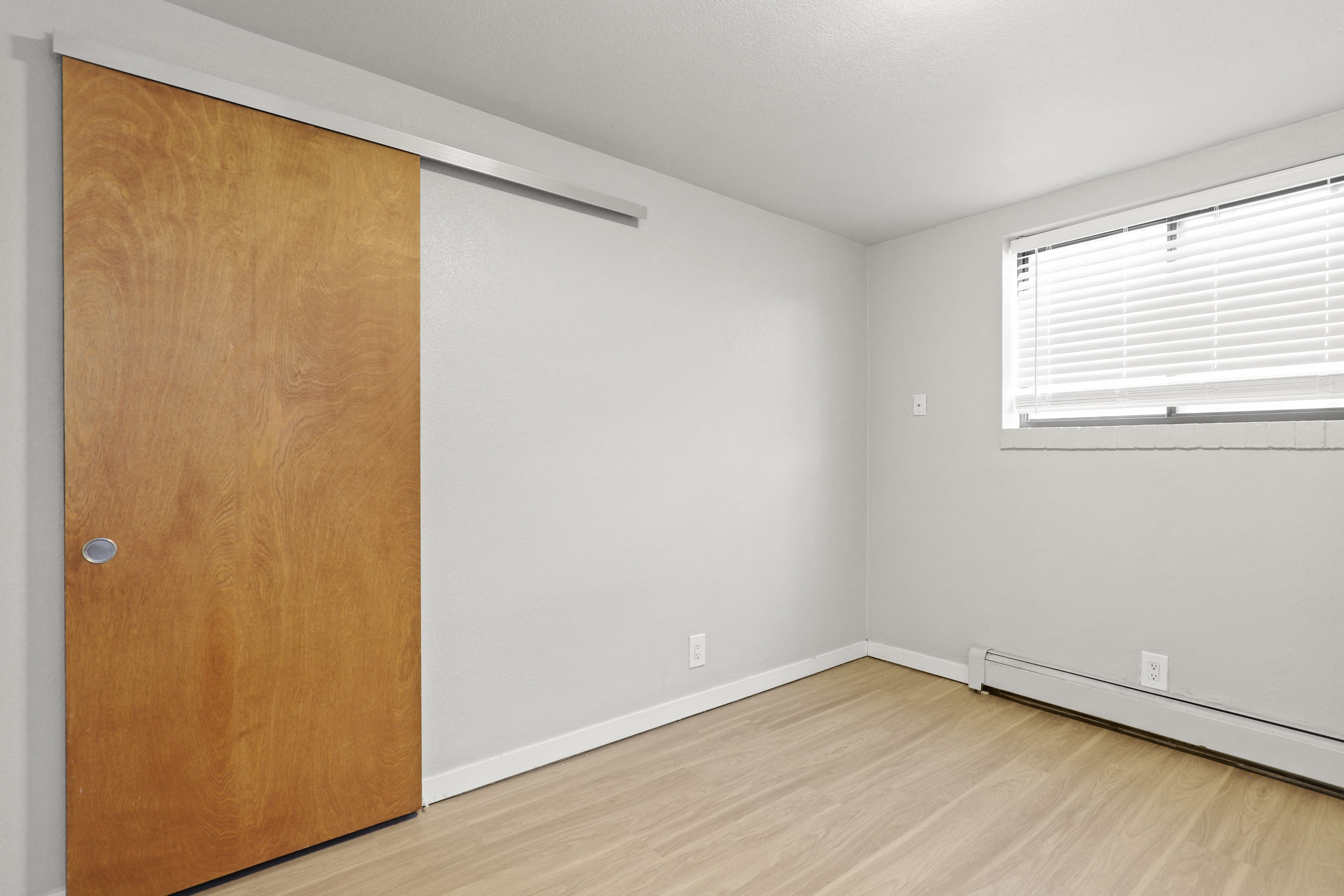 an empty room with a wooden door and a window